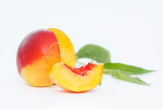Delicious and juicy nectarina peach with leaves on white background. Healthy summer fruit.