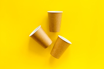 Paper cups for coffee to go on yellow background top view