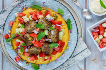 Curried chickpea cake with pistachio lamb meatballs and tomato sambal - overhead view