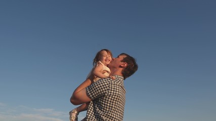 Dad throws up a happy daughter in the blue sky. Father and little child play, laugh and hug together. Happy family travels. Baby in the arms of the parent. Dad day off. The concept of a happy family