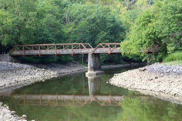 The reflecting bridge off the creek water in the park.