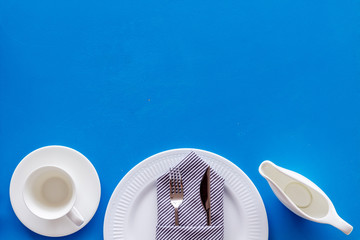 Fototapeta na wymiar White plates and sauce boat for table setting on blue background top view mock up
