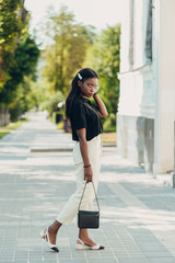 Outdoor full body fashion portrait of Young black skin girl. Model walking in street of european city.