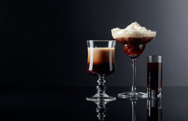 Coffee cocktails and liquor on black reflective background.