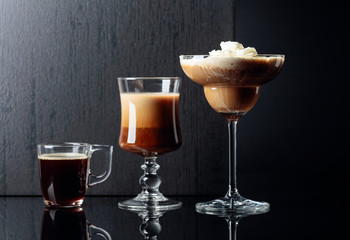Coffee cocktails and espresso on black reflective background.