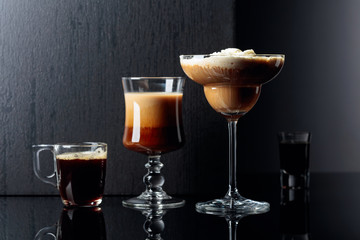 Coffee cocktails, espresso and coffee liquor on black reflective background.