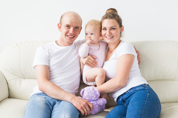Obraz premium Family and children concept - Smiling mother and father holding their newborn baby daughter at home