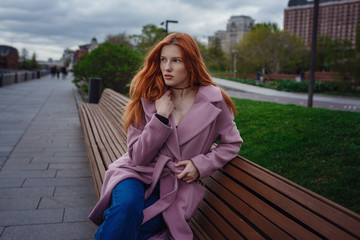 Portrait of beautiful redhair woman walking the city park.
