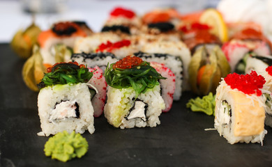 Set of sushi rolls with vasabi and ginger on a dark slate plate, Buffet table, horizontal orientation, close up