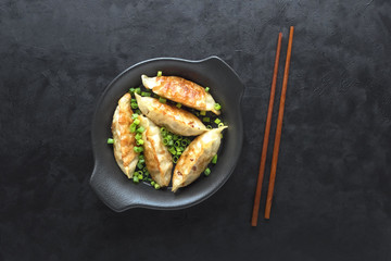 Fried dumplings Gyoza in a black plate, on a black background, top view