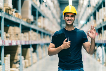 Smart Indian engineer man wearing safety helmet doing stock tick check and cardboard stock product...