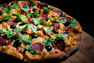 Pepperoni Pizza with Mozzarella cheese, salami, olive, pepper, Spices and Fresh basil. Italian pizza on Dark grey black slate background