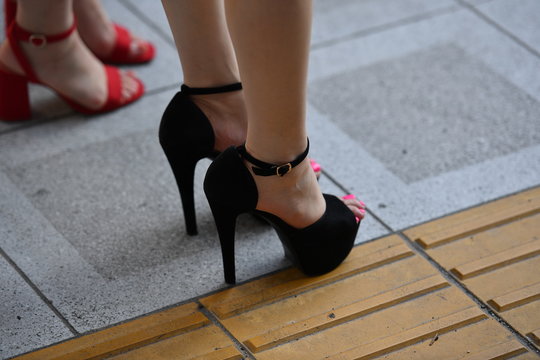 Partial view of two young Japanese woman in red and black high heels.