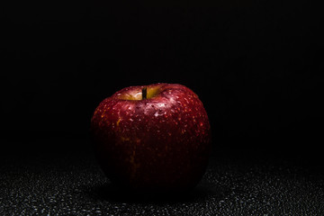 Red Apple sprenkled with Water on black Background