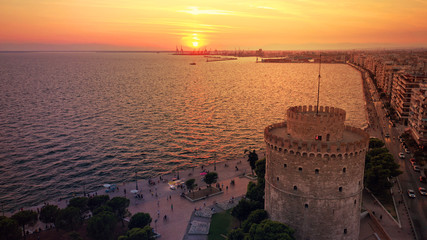 Aerial drone view of iconic historic landmark - old byzantine White Tower of Thessaloniki or Salonica at sunset with golden colours, North Greece - obrazy, fototapety, plakaty