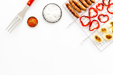Barbecue grid with grilled sausages, vegetables and spices on white background top view mock up