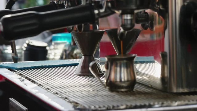 Espresso coffee poring in to metal glass from coffee machine