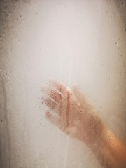 hand of a woman on glass of a shower
