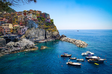 Fototapeta na wymiar MANAROLA, ITALY - JULY 4, 2019: Beautiful fishing village in Cinque Terre with colorful facades and sea view 