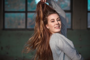 Beautiful teenage girl touching her beautiful long red hair in gray sweater