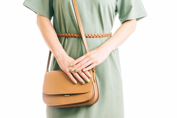 Woman in green dress standing with brown handbag.