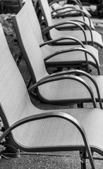 Vertical shot of a row of jute cover metal chairs in monochrome