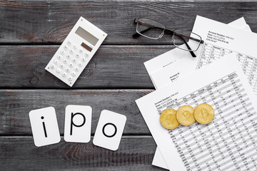 Initial Public Offering IPO with coins, calculation table, office tools on gray wooden background...