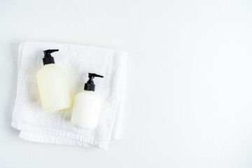 Set of Bottles with organic body care cosmetic products on white fluffy towels on a light background. Concept of SPA branding mock-up.