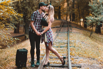 A young couple of lovers missed the train. A kiss on the rails in the autumn forest waiting for the...