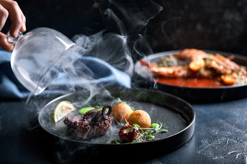Grilled grilled octopus served with smoke under the hood, food show, low key. Copy space, food fashion photo, food advertisement.