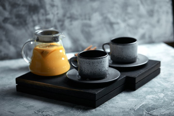 Transparent glass teapot with chitrus tea and cups, tea set on a wooden table. Close up, gray background, soft light.