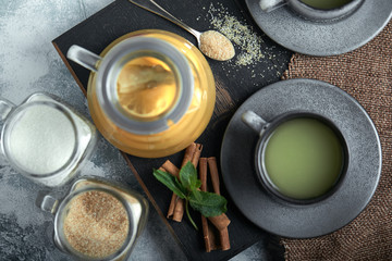 Transparent glass teapot with chitrus tea and cups, tea set on a wooden table. Close up, gray...