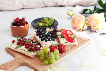 summer breakfast in bed with cheese and berry sandwiches on bread and flowers
