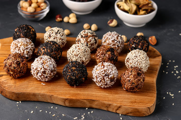 Fototapeta na wymiar Energy balls of nuts, oatmeals and dried fruit on wooden board on dark background, horizontal orientation