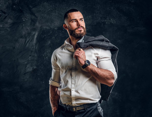 Pensive bearded businessman in white shirt is posing for photographer over dark background.