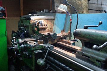 closeup of metallic lathe working against factory industrial interior background