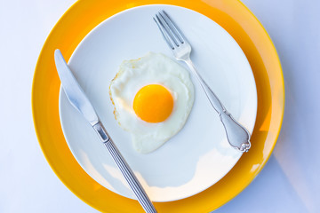 Fried egg on a white, yellow plate. Top view. Restaurant. Breakfast