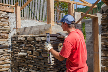 man building stone wall for house construction