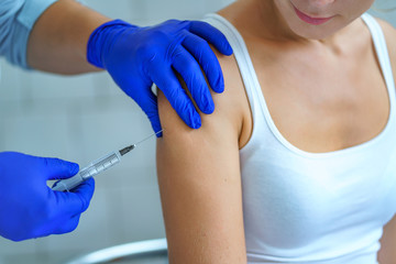 A nurse using syringe for vaccination a patient in hospital during an epidemic of influenza,...