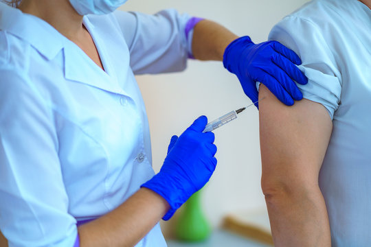 Nurse In Gloves Vaccinated Patient In Hospital Against Flu And Measles During An Epidemic. Flu Shot, Protection And Prevention Of Viral Infectious Diseases