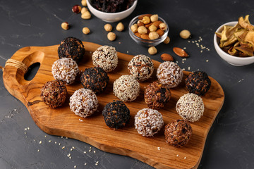 Energy balls of nuts, oatmeals and dried fruit on wooden board on dark background, horizontal...