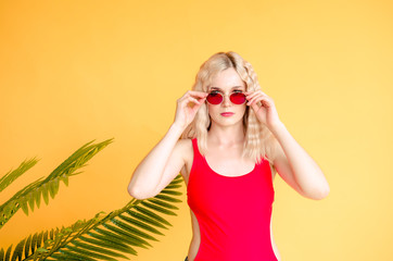 Portrait of beautiful blonde girl in sunglasses and red swimsuit