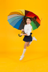 Energetic look. Adorable girl jumping with autumn look on yellow background. Cute little...