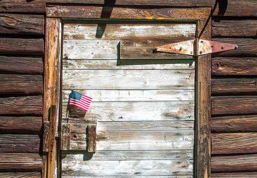  A small American flag displayed on a vintage wooden barn door in Montana with copy space