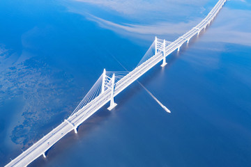 Speed ship passing under large cable stayed bridge aerial view
