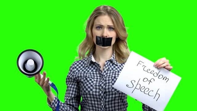 Woman holding card with inscription Freedom of speech. Young speechless woman with adhesive tape on mouth trying to speak in megaphone. Alpha Channel background.