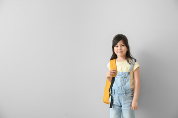 Portrait of little schoolgirl on light background