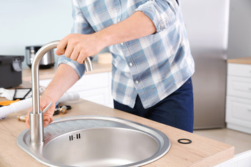 Plumber installing sink in kitchen