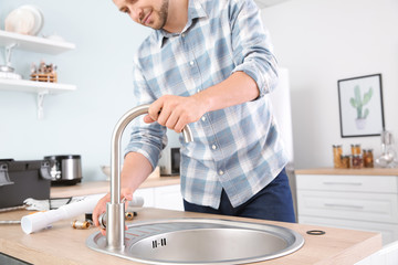 Plumber installing sink in kitchen