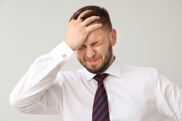 Businessman having panic attack on light background